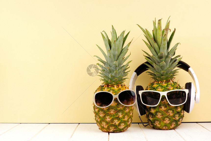 以黄色背景的太阳镜和耳机为背景的歇斯底里菠萝图片