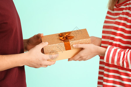 年轻情侣手握着彩色背景礼物盒图片