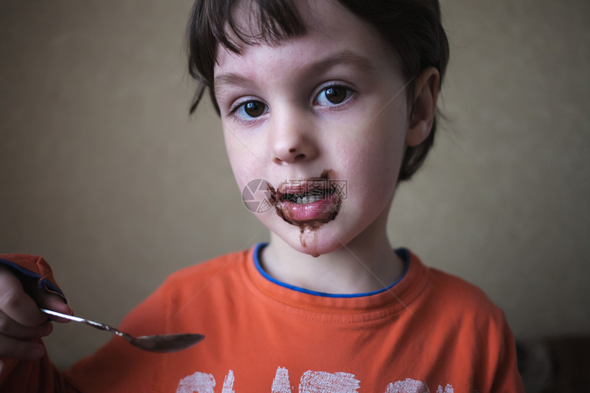男孩用勺子吃饭婴儿被食物弄脏了一个脸很脏的孩子一图片