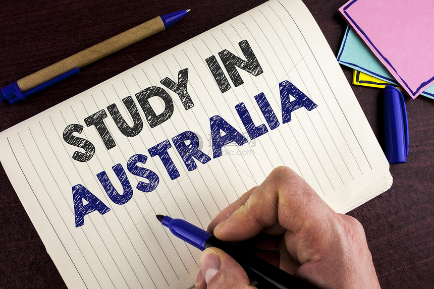 概念手写显示在澳大利亚商业照片展示了由ManNotebookBook木制背景笔书写的海外大学毕业图片