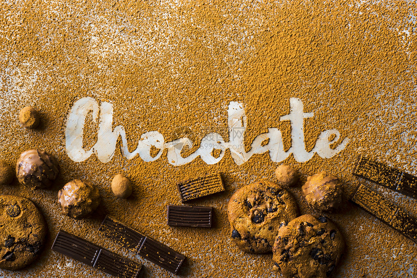 巧克力这个词印在可粉和巧克力曲奇饼干巧克力片巧克力和糖果中的坚果之间的灰色背景上我图片