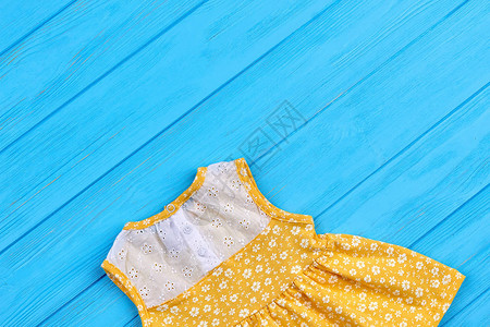 有刺绣的黄色小礼服新生女婴穿着蓝木本底的散装服图片
