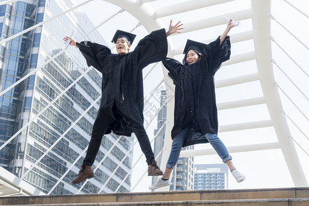 快乐的毕业生青少年在祝贺仪式上跳跃着毕业礼服图片