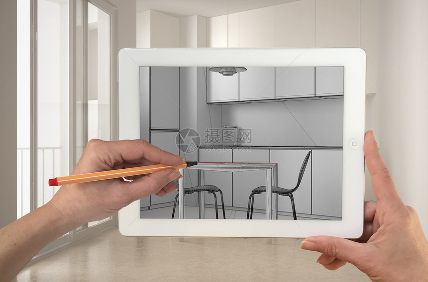 手持和绘图显示现代厨房CAD草图的平板电脑背景中真正完成的极简主义白色和木质厨房图片