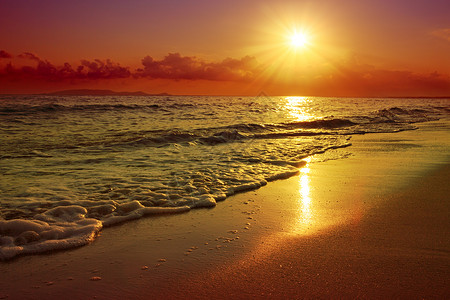 黄金日落有海浪和沙图片