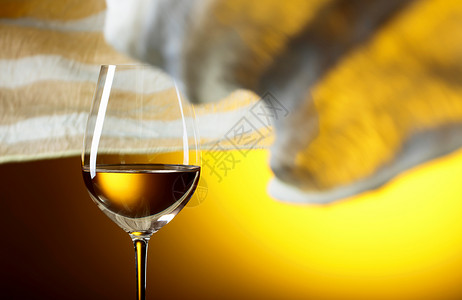 黄色背景的白葡萄酒杯子黄色织物在风中飘图片