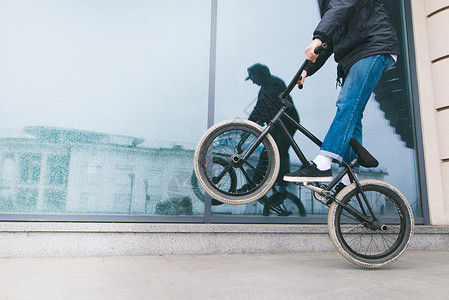 一名男子骑着BMX后轮的自行车靠在玻璃橱窗上一名青少年在自图片