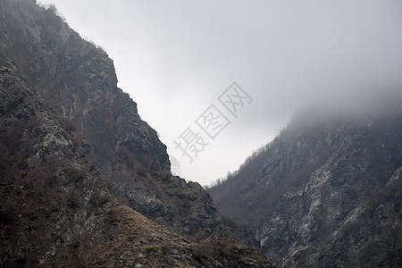 雪和岩石山中雾蒙的冬季景观全景图片