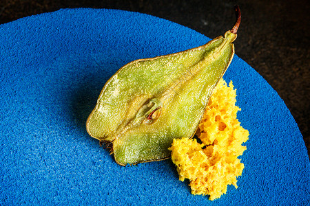 用干梨和黄色海绵蛋糕片装饰的蓝色圆形蛋糕的顶部图片