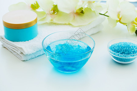 蓝色浴盐润肤霜和贝壳在白桌背景上的水疗中心图片