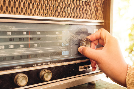 复古生活方式女人手调整按钮老式收音机听音乐或新闻图片