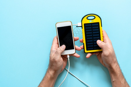 一个男人手中蓝色背景的设备的黄色太阳能电池从太阳能电池板为图片