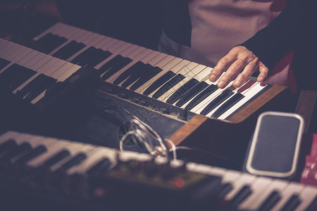 演奏老式合成器键盘时音乐家的手图片
