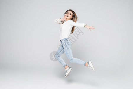 微笑的年轻女子在空中跳跃与高举拳头在图片