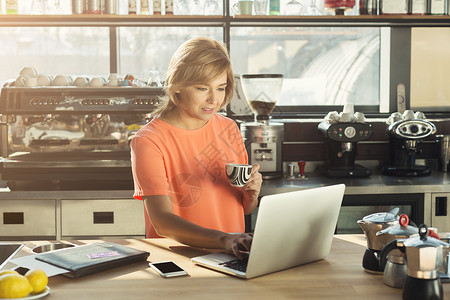 中年女咖啡师或经理在笔记本电脑上工作图片