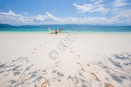 白沙滩上的脚印乘船旅游和浅蓝天空图片