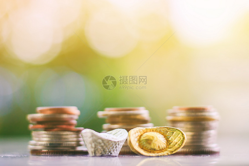 金银sycee或元宝船锭与模糊的硬币堆和自然绿色背景的投资商业和金融概念图片