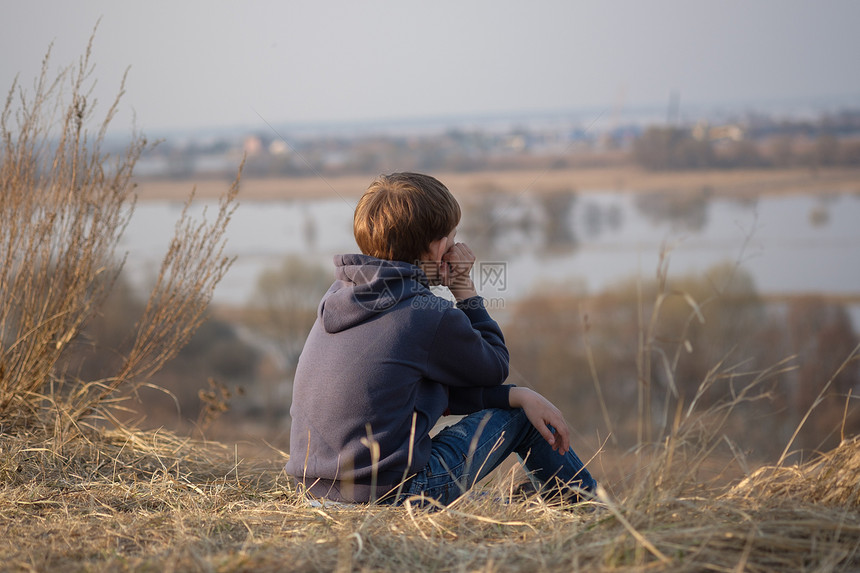 欧洲可爱的男孩深思熟虑地坐在泉水岸边图片