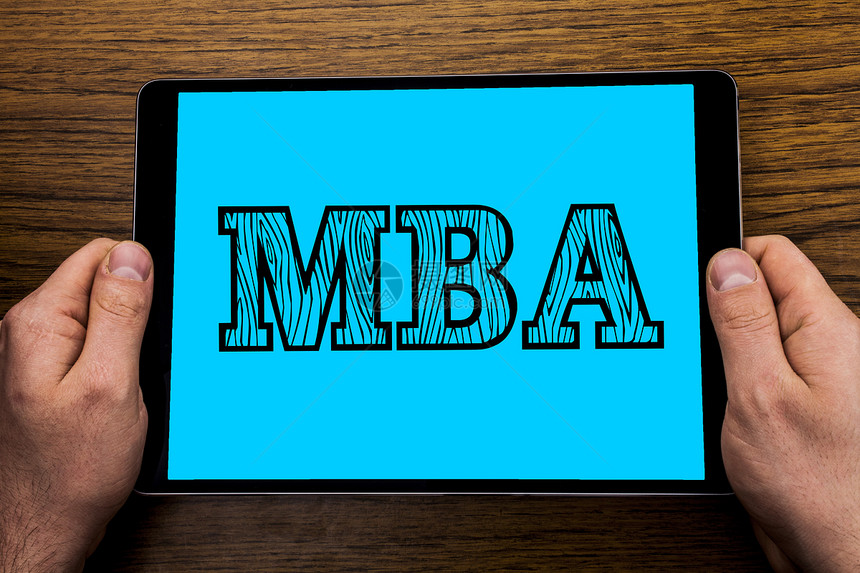 学院研究后商业管理高级学位概念硕士用手制木质背景持有的平板屏幕书面文字符号显示Mba图片