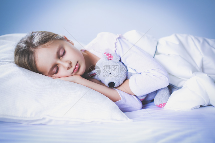 小女孩抱着玩具泰迪熊睡在床上图片