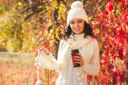 秋天背景下喝茶或咖啡的年轻美女图片