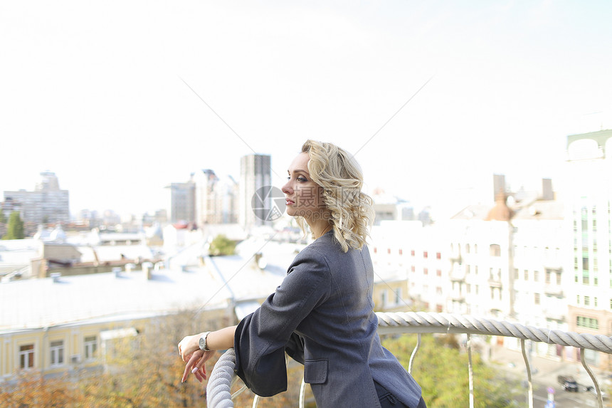 漂亮的女站在有城市景观背景的阳台上时尚和城市生图片