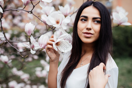 年轻美丽的caucasian女孩在盛开的春天木兰花园里图片