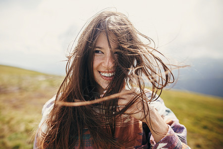 快乐的旅行者时髦女孩与风的头发和微笑图片
