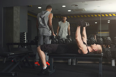 两个运动员在健身房用哑铃操练图片