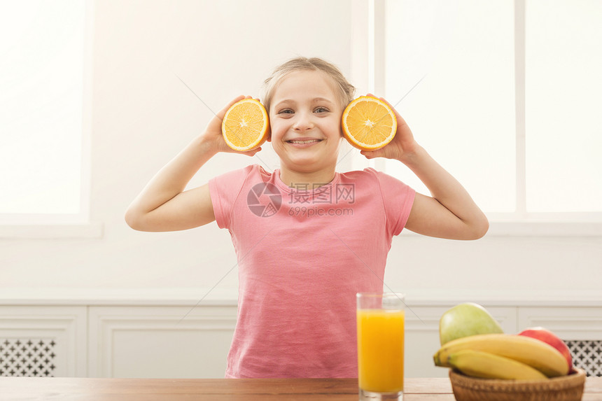 快乐的小女孩站在白色背景上用橘子玩得开心儿童健康食品概图片