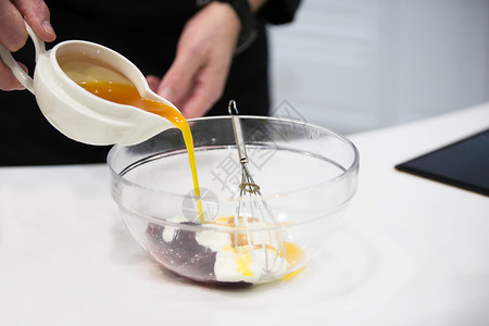 烹饪甜点用打蛋器将酱汁倒入玻璃碗中图片