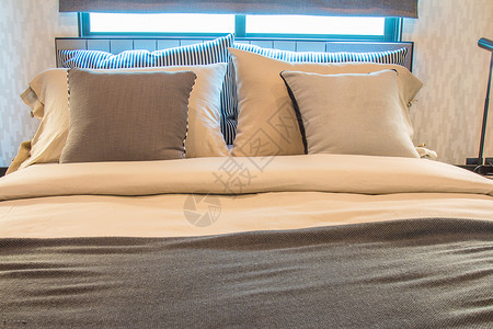 浅褐色枕头和床上的棕色毯子卧室里有现图片