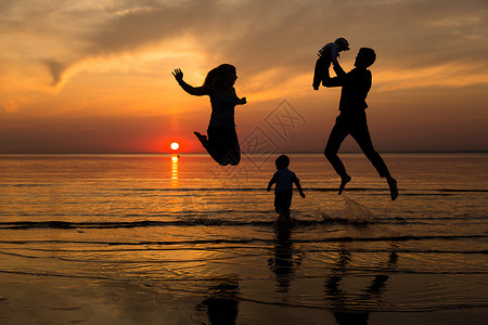 夕阳下海边的一家人图片