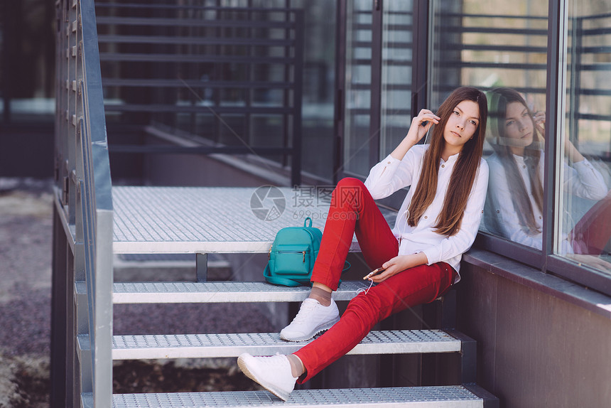 一个手拿着智能手机的少女在户外花时间度过时光美图片