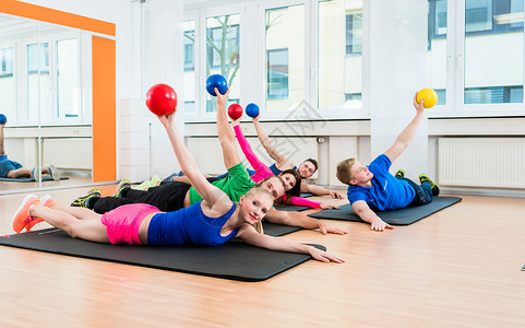 男女在瑜伽垫上用体操中的药球背景图片