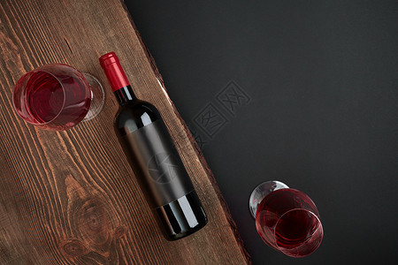黑色背景的木板上装着一瓶酒和两杯眼镜图片