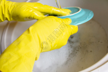 用黄色手套洗碗男人的手图片