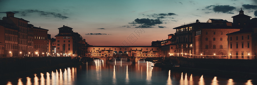 晚上在意大利佛罗伦萨的阿诺河全景上的老桥背景图片