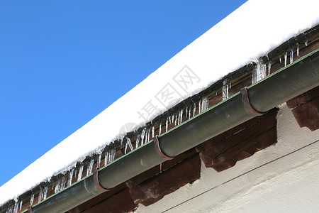 冬季大雪过后屋顶上有冰柱的排水沟图片