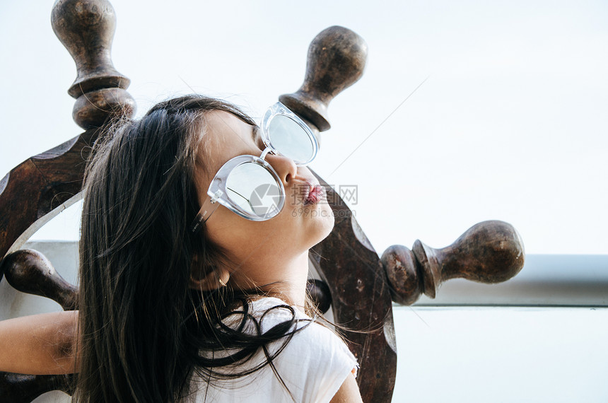 小女孩在阳台上玩水手的游戏用船舵和海洋背景来图片