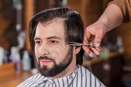 英俊的年轻人在理发店理发的特写镜头图片