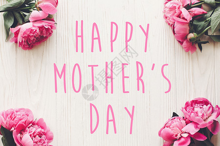 母亲节快乐的文字在质朴的白色木制背景上的粉红色牡丹花束上图片