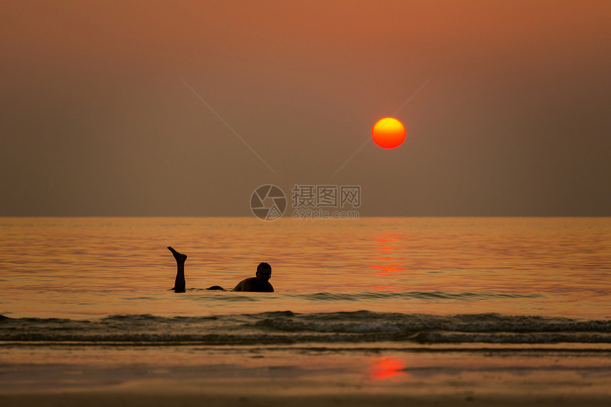 在泰国的KohMook岛上的热带日落与年轻游客在查理海滩上拍摄的海中景观图片