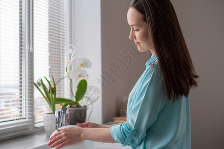 家庭主妇在厨房窗户前洗盘子在清晨图片