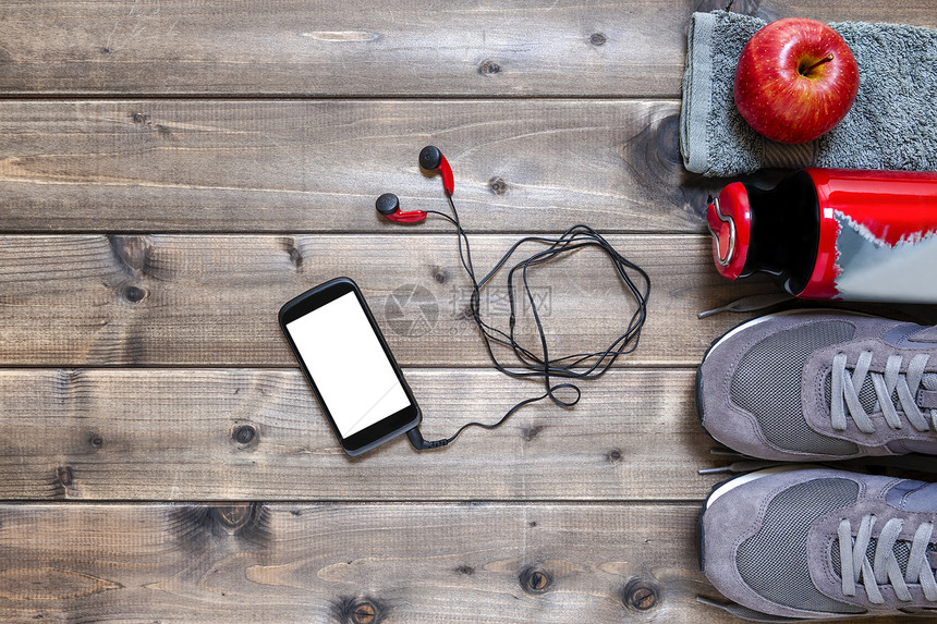 红色苹果运动鞋耳机智能手机毛巾和水瓶的顶端景象图片