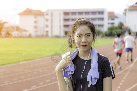 亚洲女孩听音乐穿运动服背景公共体育场图片