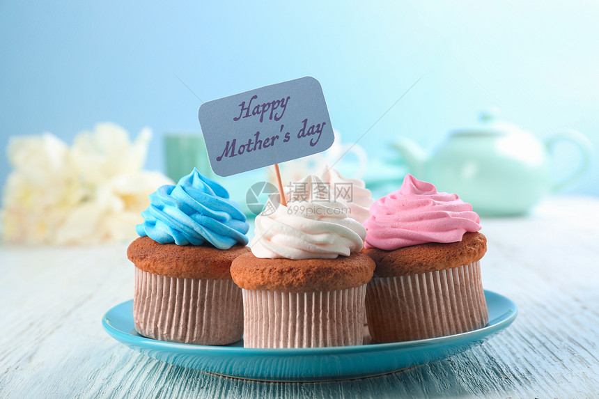 美味的纸杯蛋糕和尖嘴小蛋糕上面写着欢乐母亲在图片