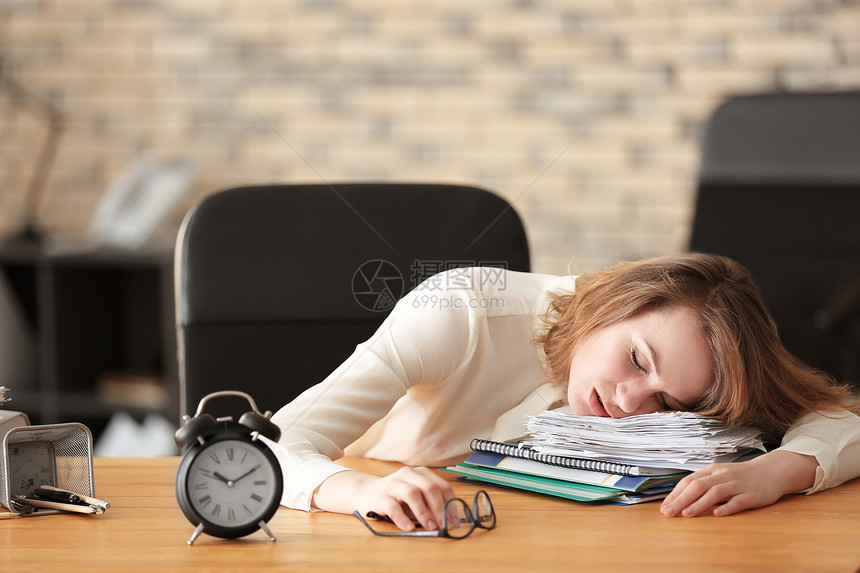 成熟疲惫的女人睡在办公室的桌子上时间管理念图片