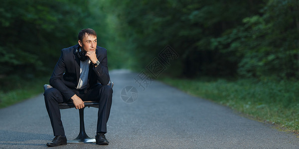穿着商业西装和耳机的帅男坐在林图片
