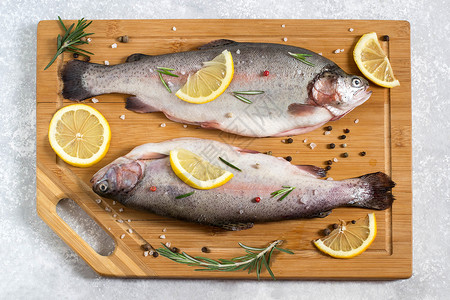 两条新的鲑鱼在切菜板上和烹饪的原料派果盐柠檬调味图片